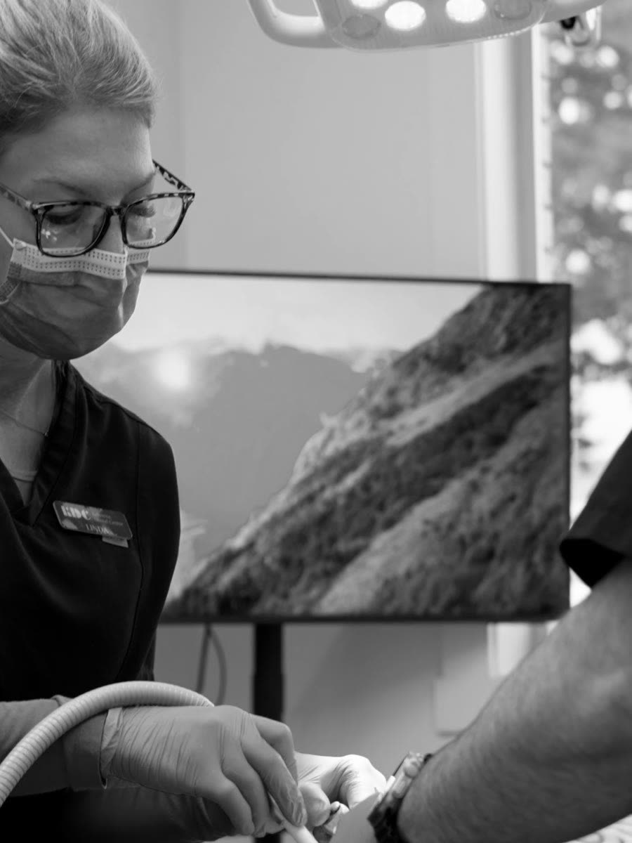 A certified dental assistant working chairside in an operatory at Kelowna Dental Centre.